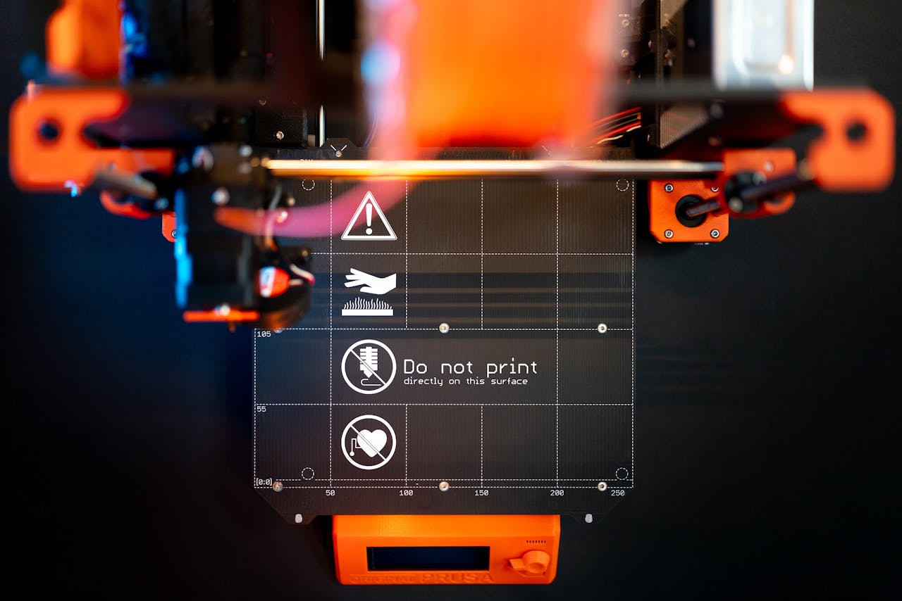 Detailed image of a 3D printer with caution signage, showcasing advanced manufacturing.